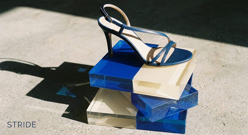 Navy strappy heeled sandal on stacked blue acrylic blocks in sunlight