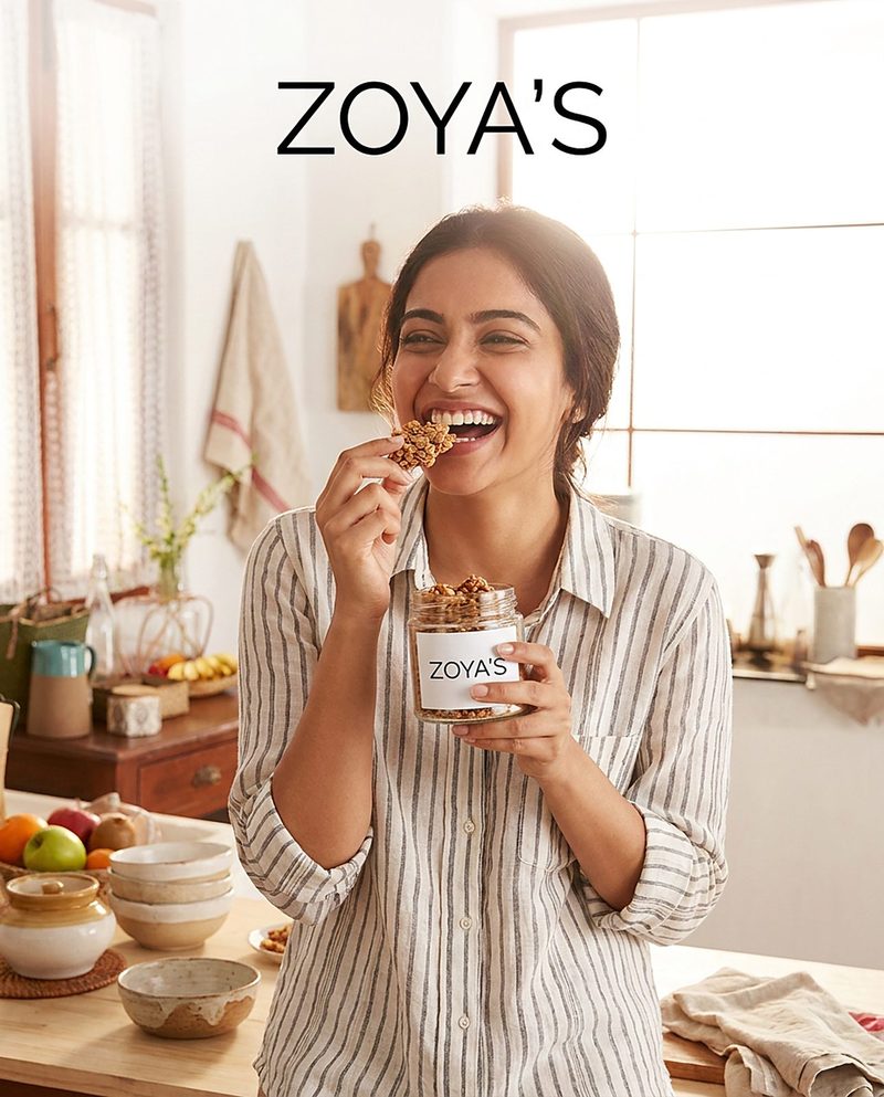Laughing woman eating granola from a jar in a bright kitchen