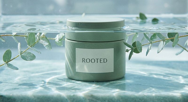 Mint-green cream jar with eucalyptus sprigs on a wet marble surface