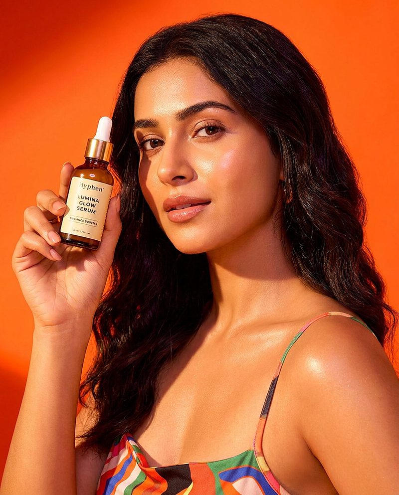 Woman holding an amber serum bottle against a bright orange backdrop